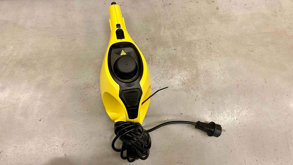Ein getesteter Dampfreiniger von oben auf einer grauen Fläche liegend.