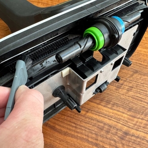 Eine Hand reinigt das Bodenstück des Kärcher FC 4-4 mithilfe eines Reinigungspinsels