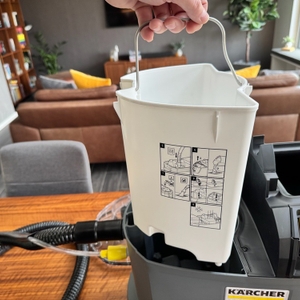 Eine Hand hebt den Wasserbehälter des Kärcher Puzzi 8/1 heraus