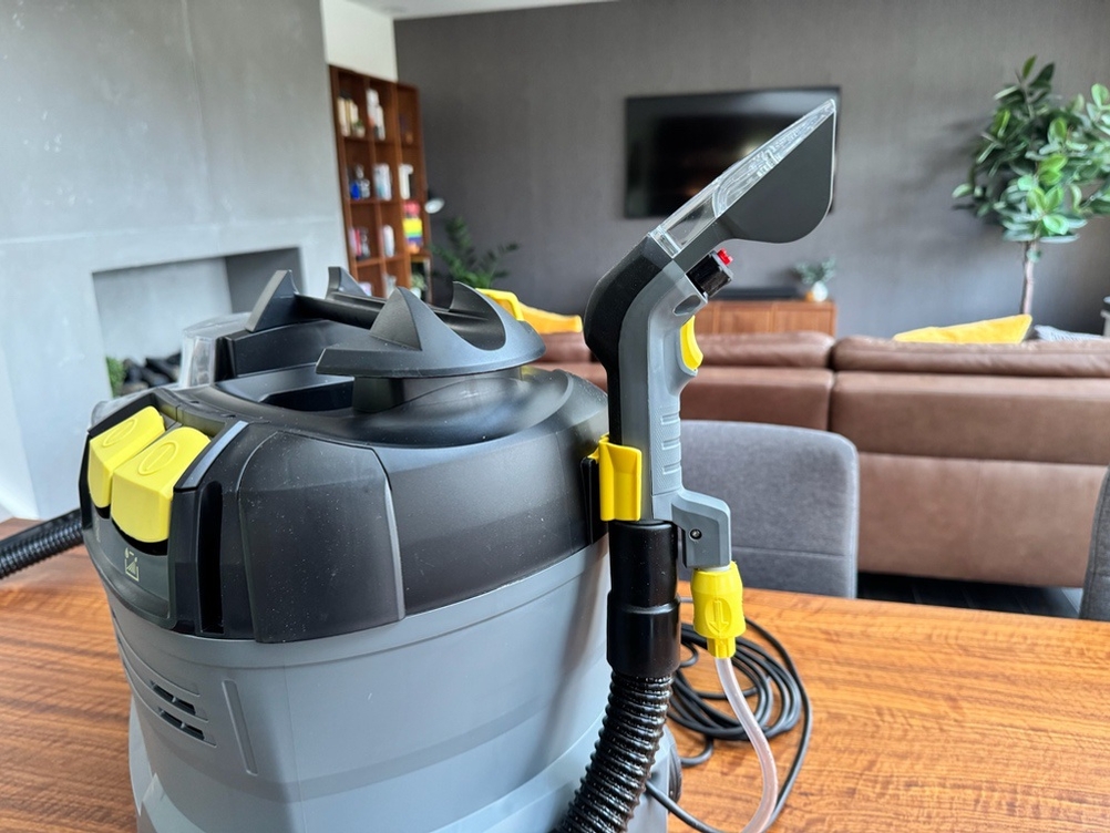 Der Kärcher Waschsauger Puzzi 8/1 steht auf einem Wohnzimmertisch.