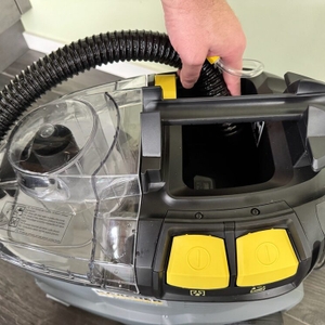 Eine Hand hält einen Schlauch in den Tank des Kärcher Puzzi 8/1