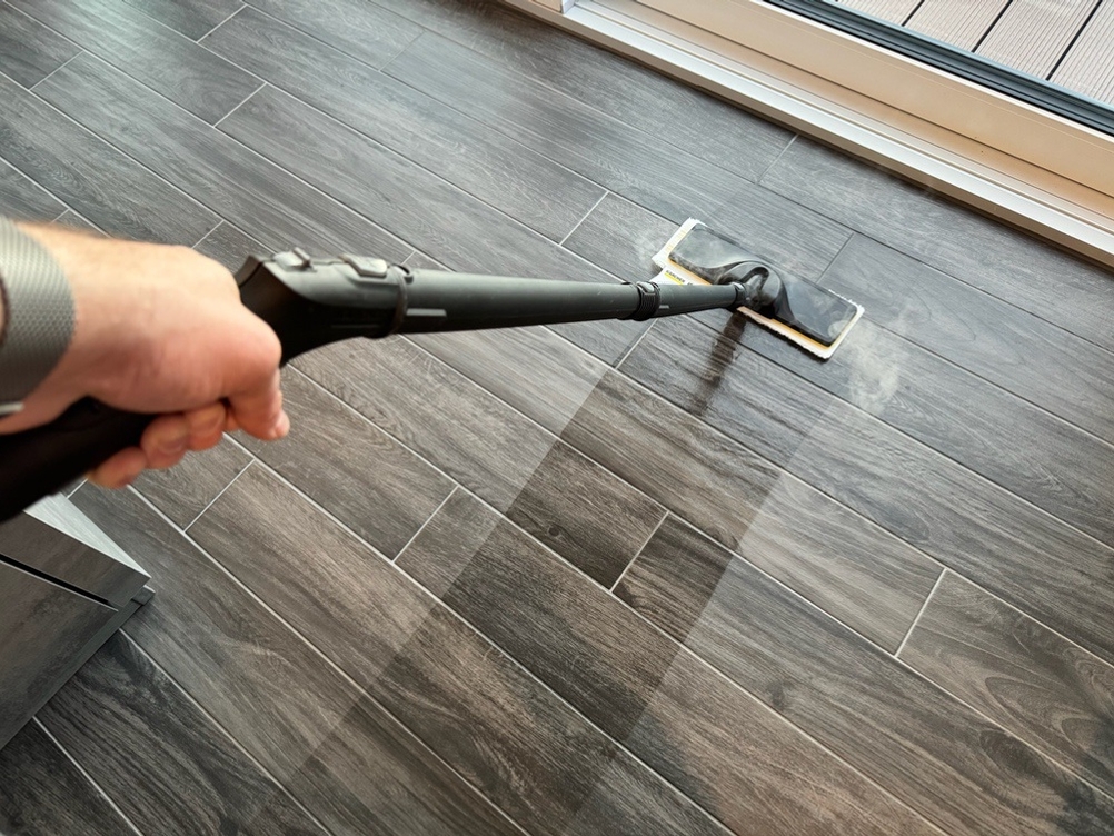 Eine Hand reinigt Fliesenboden mithilfe des Kärcher SC 4 Deluxe