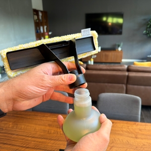 Eine Hand schraubt den Deckel von der Sprühflasche der Kärcher WV 2 Black Edition