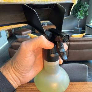 Eine Hand hält die Sprühflasche mit integriertem Wischer vom Kärcher WV 2 Black Edition in der Hand