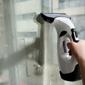 Der Kärcher WV 5 Plus wird an einer nassen Glasscheibe verwendet. Tropfwasser ist auf der Scheibe sichtbar.