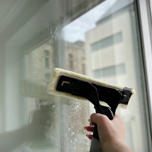 Ein Fenster wird mit dem Mikrofaserwischer des Kärcher WV 5 Plus gereinigt. Deutlich erkennbar ist der feuchte Wasserfilm.