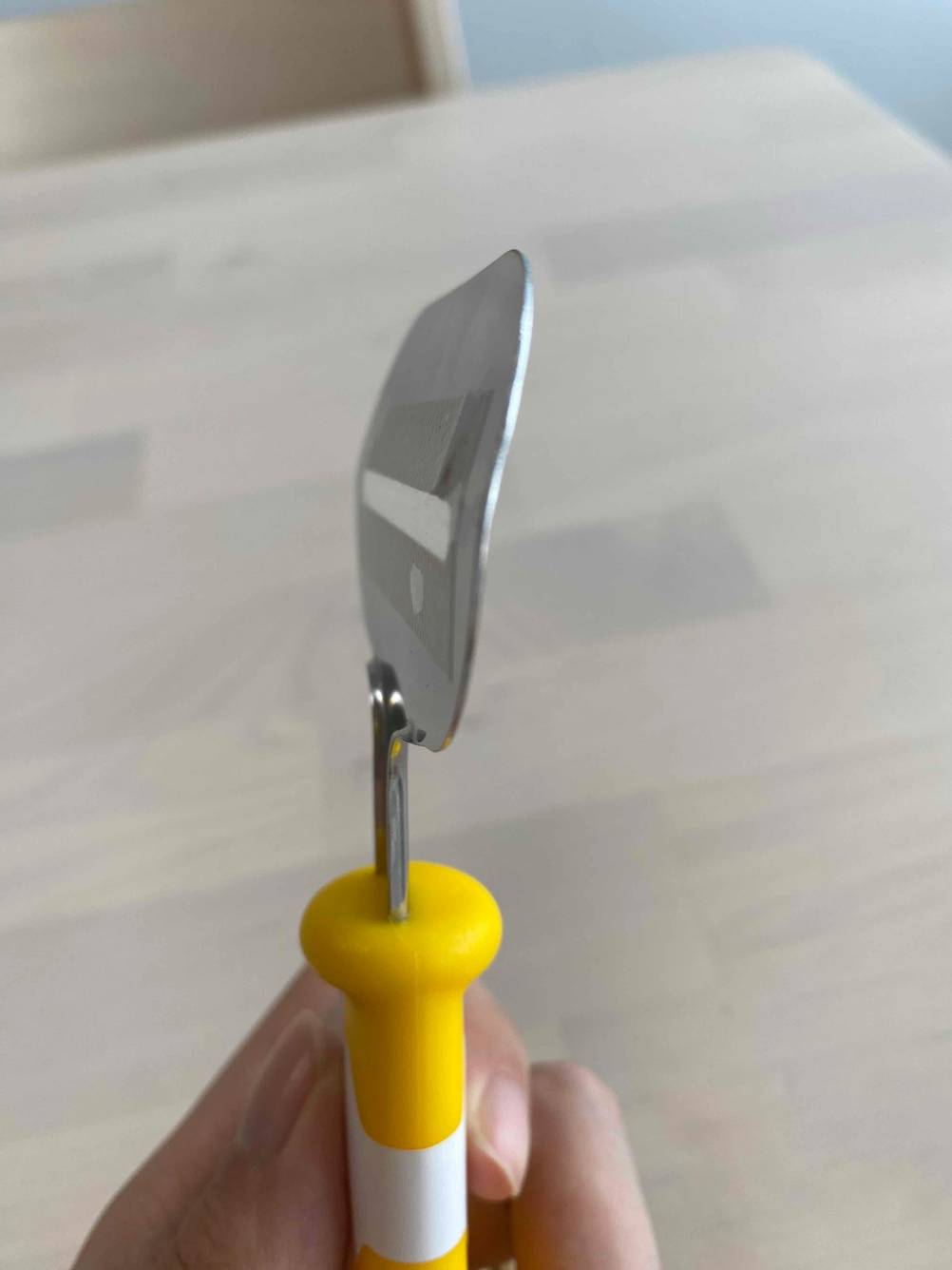 Seitenansicht eines getesteten Käsehobels von einer Hand gehalten.