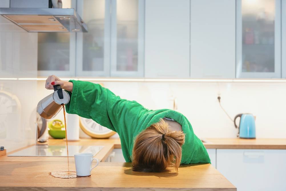 Müde Frau gießt den Kaffee neben ihre Tasse.