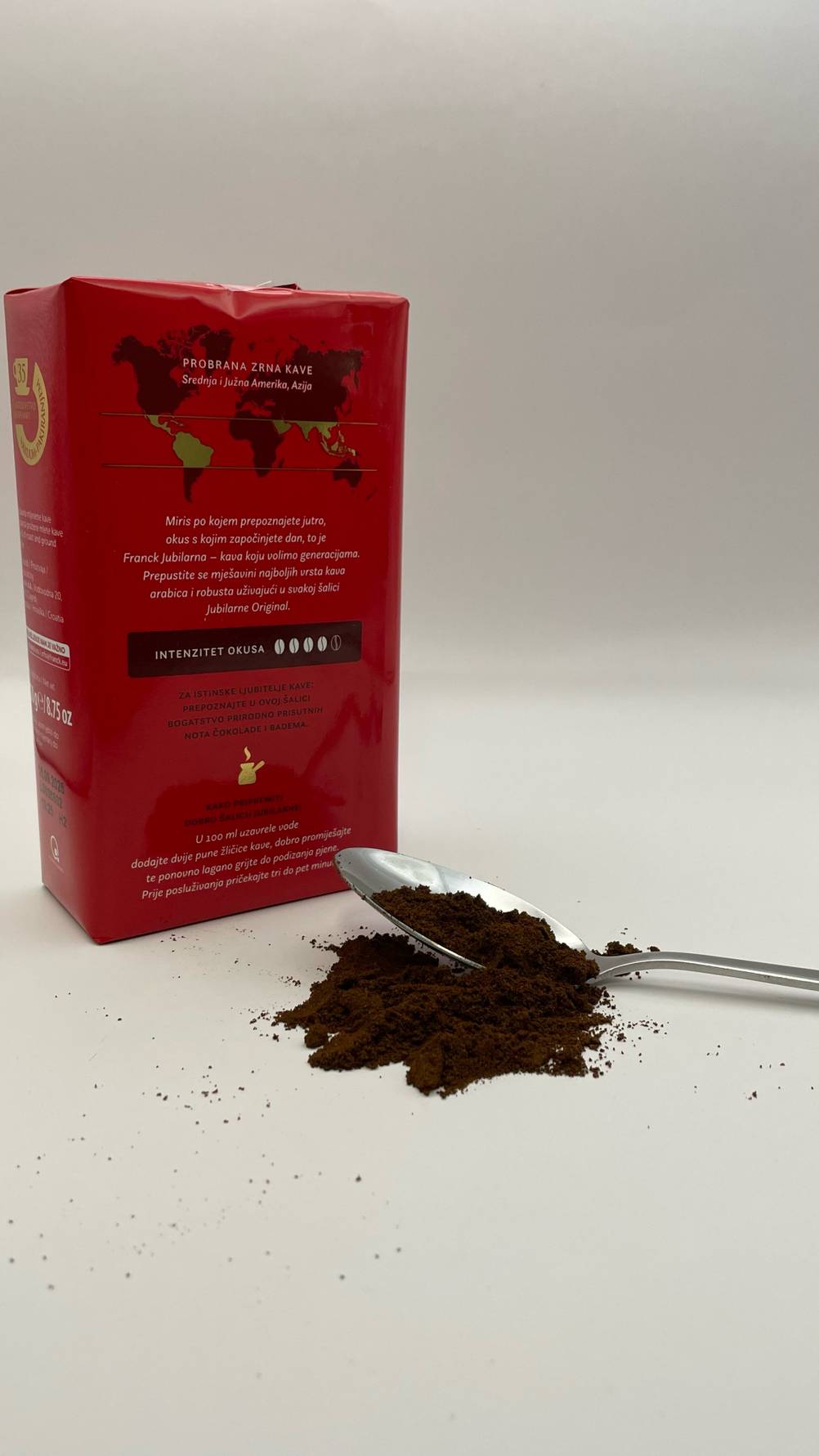 Eine Packung des Kaffee Trommelröstung im Test mit der Rückseite nach vorne, ein Löffel mit Kaffeepulver davor.
