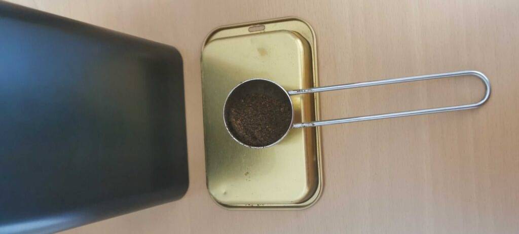 Kaffeedosen im Test: eine rechteckige schwarze Kaffeedose steht neben einem Kaffeelöffel voller Pulverkaffee.