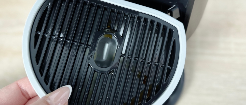 Die Abtropfschale der Krups Nescafé Dolce Gusto Mini Me KP120H wird herausgenommen. Auf der Oberfläche befinden sich leichte Kaffeerückstände.