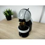 Die Krups Nescafé Dolce Gusto Mini Me KP120H steht auf einem Holztisch. Eine schwarze Tasse steht unter dem Kaffeeauslauf.