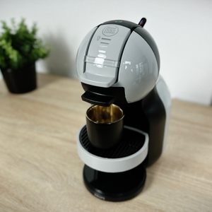 Die Krups Nescafé Dolce Gusto Mini Me KP120H steht auf einem Holztisch. Eine schwarze Tasse steht unter dem Kaffeeauslauf.