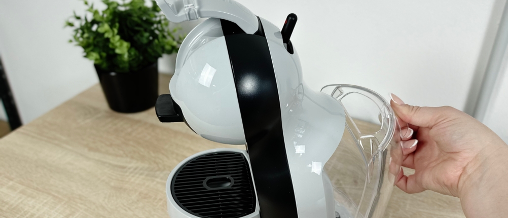 Eine Hand zieht den Wassertank der Krups Dolce Gusto Mini Me KP120H nach hinten heraus. Der Tank ist transparent.