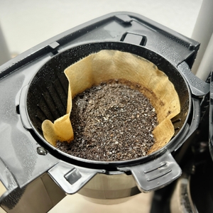 Der Filterhalter der Krups KM8328 ist geöffnet und zeigt feuchtes, verbrauchtes Kaffeemehl im Filter. Kondenswasser ist am Rand sichtbar.