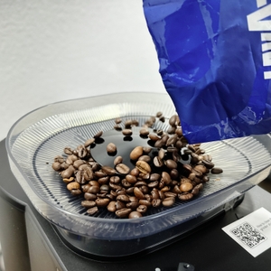 Kaffeebohnen werden in den Bohnenbehälter der Krups KM8328 eingefüllt. Eine geöffnete Packung Lavazza ist im Bild zu sehen.