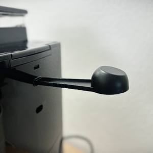 Ein schwarzer Dosierlöffel ist seitlich an der Kaffeemaschine befestigt. Er dient zum Abmessen von Kaffeepulver bei Bedarf.