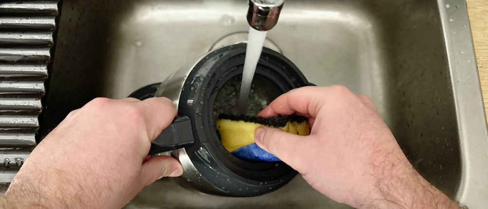 Die Thermoskanne der Russell Hobbs Grind & Brew wird per Hand unter fließendem Wasser gereinigt. Eine Hand hält einen Schwamm im Inneren.