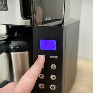 Das beleuchtete Display der Russell Hobbs Grind & Brew zeigt Uhrzeit und Symbole an. Die Bedientasten befinden sich direkt darunter.