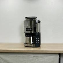Die Russell Hobbs Grind & Brew steht vollständig aufgebaut auf einer hellen Arbeitsfläche. Das gesamte Gerät mit Glaskanne und Bedienelementen ist sichtbar.