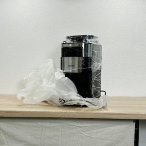 Die Severin KA 4814 steht nach dem Auspacken in ihrer transparenten Schutzfolie auf einer Arbeitsplatte. Teile der Folie liegen seitlich.