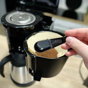 Ein Filterlöffel mit Kaffeepulver wird über den eingesetzten Kaffeefilter in der Rowenta CT3818 gehalten. Der Brühkopf ist sichtbar.