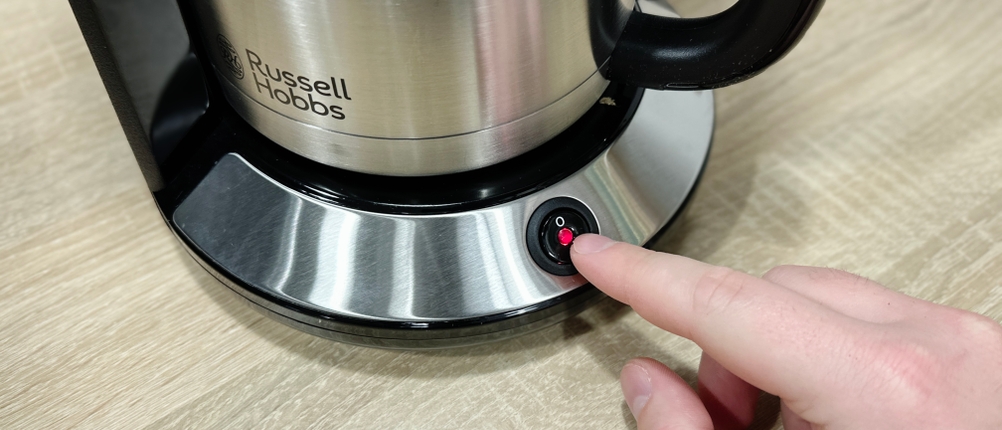 Eine Hand drückt den Einschaltknopf an der Front der Rowenta Milano CT3818 Kaffeemaschine. Der Edelstahlkörper der Thermoskanne ist daneben zu sehen.