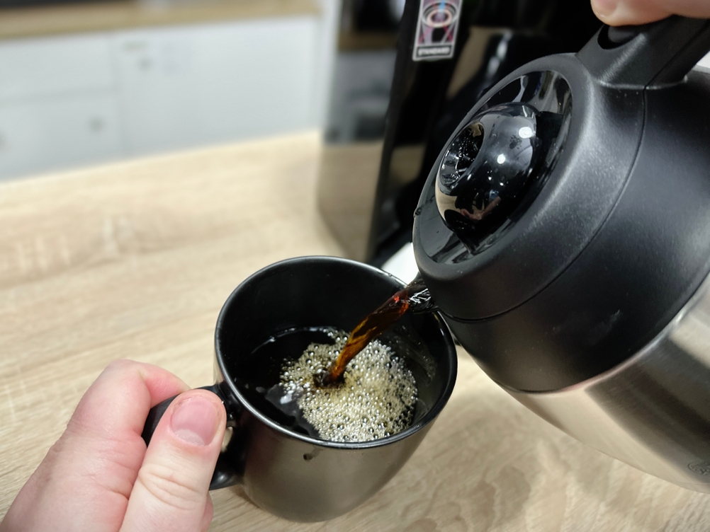 Frisch gebrühter Kaffee wird aus der Thermoskanne der Russell Hobbs Adventure in eine schwarze Tasse gegossen.