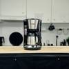 Die Russell Hobbs Adventure Thermo-Kaffeemaschine steht mittig auf einer Holzplatte. Die Küche ist im Hintergrund sichtbar.
