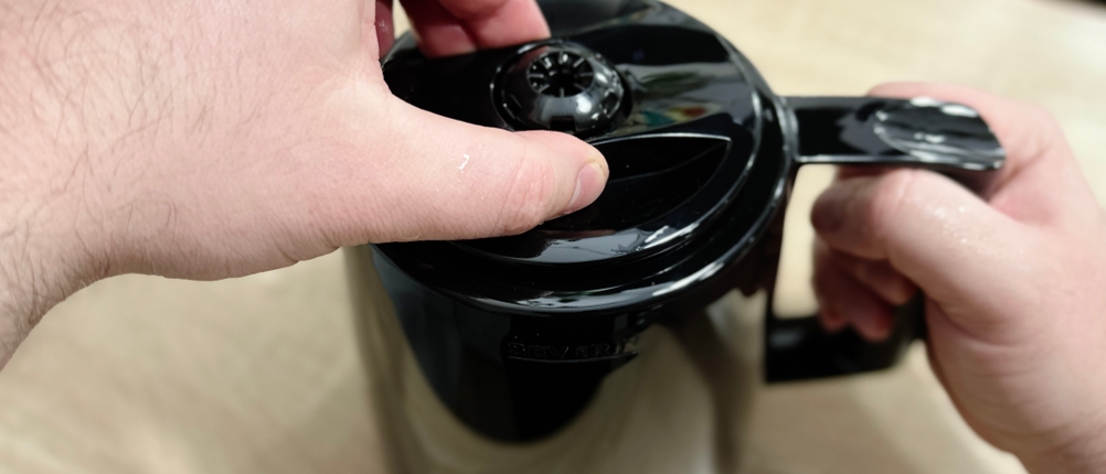 Eine Hand öffnet den Deckel des Schwenkfilters an der Severin KA 9250 Kaffeemaschine. Das Filterfach ist sichtbar.