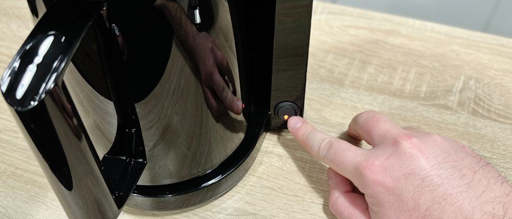 Eine Hand schaltet die Severin KA 9250 Kaffeemaschine über den beleuchteten Kippschalter ein. Die Kanne ist eingesetzt.