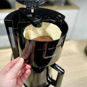 Die Severin KA 9250 zeigt ihren geöffneten Filterhalter mit eingesetztem Papierfilter und frischem Kaffeepulver.