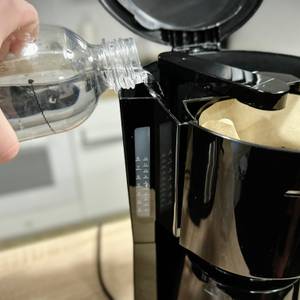 Wasser wird aus einer Flasche in den geöffneten Wassertank der Severin KA 9250 eingefüllt.
