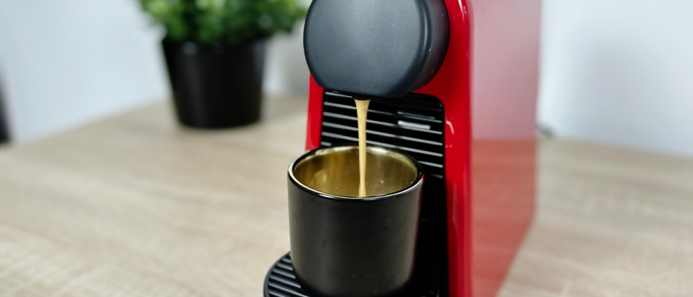 Ein Espresso wird mit der Nespresso De’Longhi Essenza Mini zubereitet. Der Kaffee läuft in eine schwarze Tasse.