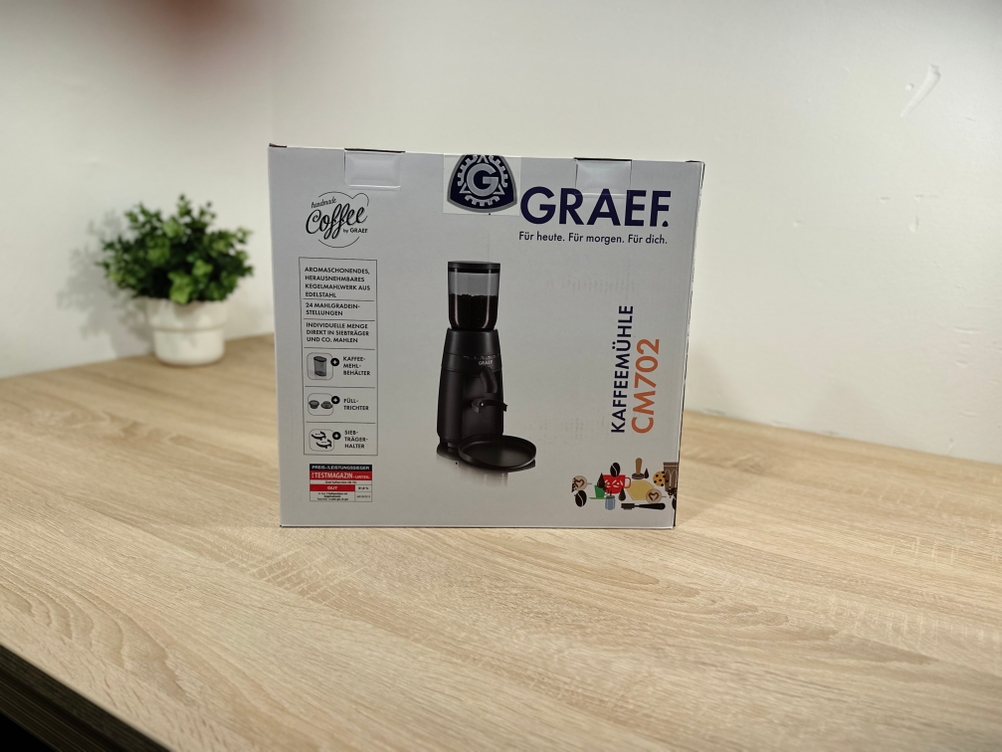 Die Verpackung der Kaffeemühle für Siebträger von Graef steht auf einem Tisch.