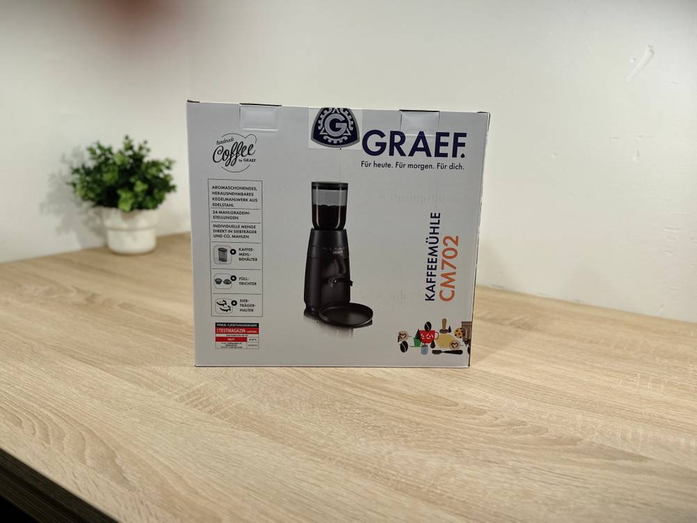 Die Verpackung der Kaffeemühle für Siebträger von Graef steht auf einem Tisch.