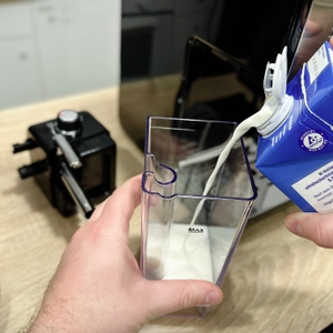 Milch wird aus einem Tetrapack in den entnommenen Milchbehälter der Breville Prima Latte II VCF108X gegossen. Der Behälter steht auf der Arbeitsfläche.