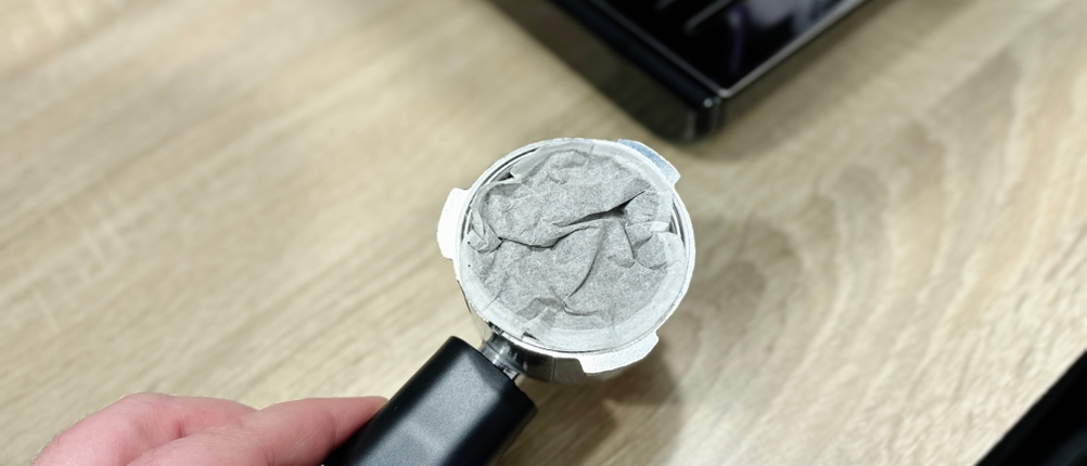 Ein benutztes Kaffeepad liegt im eingespannten Siebträger der Breville Prima Latte II VCF108X. Das Pad ist feucht und leicht verformt.