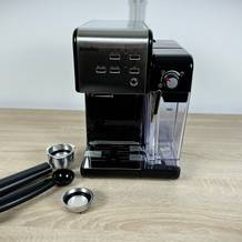 Die Breville Prima Latte II VCF108X steht komplett aufgebaut auf einem Holztisch. Alle Hauptkomponenten sind sichtbar, inklusive Milchbehälter.