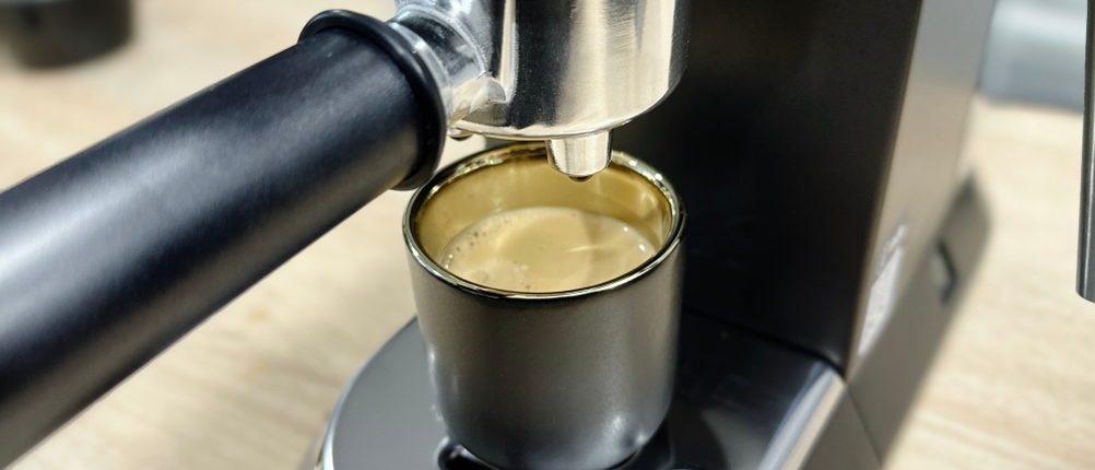 Ein frisch gebrühter Espresso fließt aus dem Auslauf der De'Longhi Dedica Style EC 685.B in eine schwarze Tasse. Die Crema ist gut sichtbar.