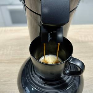 Frisch gebrühter Kaffee läuft aus der Philips Senseo New Original HD6554/68 in eine schwarze Tasse. Die Crema ist gut erkennbar.
