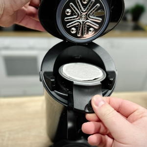 Ein Senseo-Kaffeepad wird in die Brühkammer der geöffneten Philips Senseo HD6554/68 eingelegt. Der Deckel ist vollständig aufgeklappt.