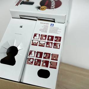 Die Verpackung der Philips Senseo HD6554/68 ist geöffnet. Eine Schnellstart-Anleitung mit Bildern ist auf der Lasche abgedruckt.