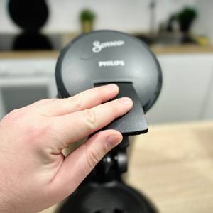 Der Deckel der Philips Senseo HD6554/68 wird von Hand geöffnet. Die Brühkammer ist bereits sichtbar.