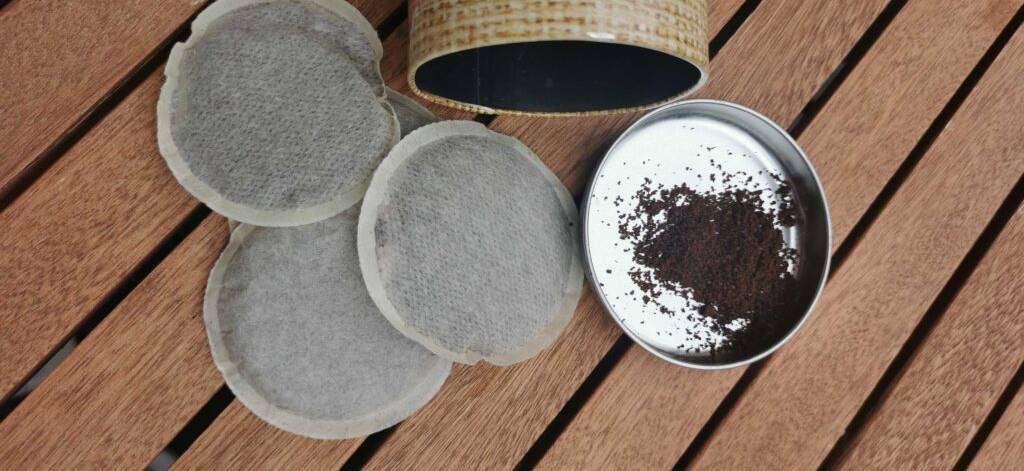 Getestete Kaffeepads liegen neben einer geöffneten Dose mit Pulverkaffee auf dem Deckel.