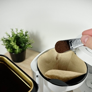 Gemahlener Kaffee wird mit einem Messlöffel in den Filtereinsatz der Melitta Look V Perfection eingefüllt. Der Schwenkfilter ist geöffnet.