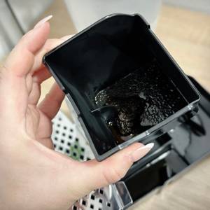 Der Kaffeesatzbehälter des Philips Series 5400 (EP5447/90) wird zur Reinigung entnommen. Der nasse Trester ist gut erkennbar.