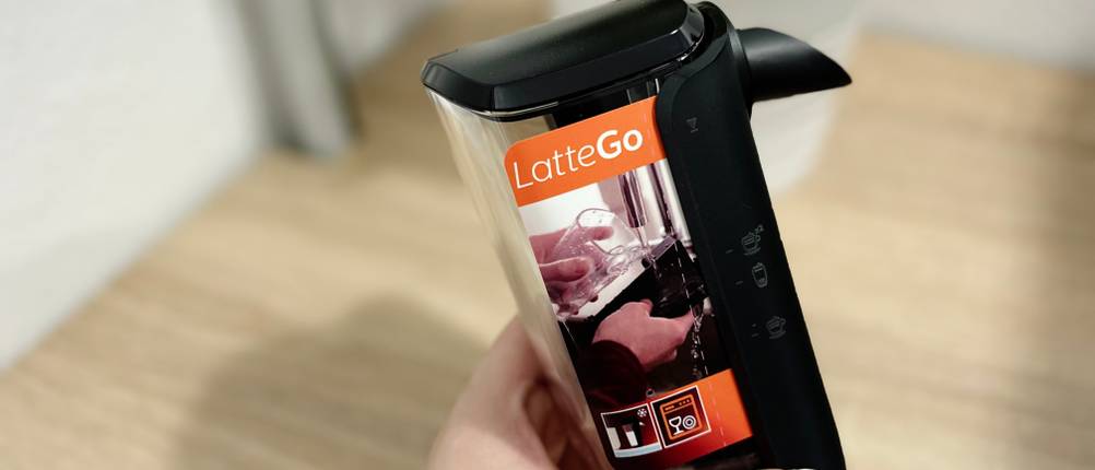 Der LatteGo-Milchbehälter des Philips Series 5400 (EP5447/90) wird in der Hand gehalten. Die Verpackung weist auf einfache Reinigung hin.