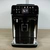 Frontalansicht des Philips Series 5400 (EP5447/90) Kaffeevollautomaten auf einer Arbeitsplatte. Das Touchdisplay ist beleuchtet.