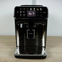 Frontalansicht des Philips Series 5400 (EP5447/90) Kaffeevollautomaten auf einer Arbeitsplatte. Das Touchdisplay ist beleuchtet.